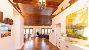 A spacious living area with wooden flooring, a fireplace, and a large painting of a landscape. - Sweet Water Estate (Butler)