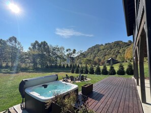 Uma banheira de hidromassagem em um deck de madeira, com vista para uma encosta arborizada.