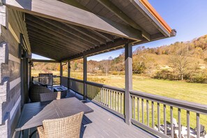 Um alpendre coberto com mesa e cadeiras, com vista para uma paisagem gramada.