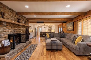 A spacious living area with a stone fireplace, a large sectional sofa, and a wooden ceiling. - A River Cliff View (Sugar Grove)
