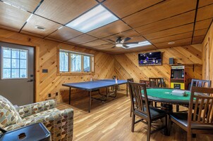 Una habitación con mesa de ping pong, mesa de billar y televisor montado en la pared.