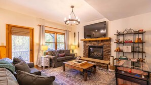 A cozy living room with a fireplace, a sofa, a coffee table, and a TV. - Appalachian Seasons Hot tub Fire Place Seasonal Views (Banner Elk)