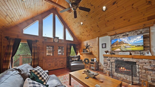 Una sala de estar acogedora con chimenea, techo de madera y ventanas grandes.