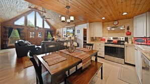 Una cocina amplia con armarios de madera, un comedor con mesa de madera y una sala de estar con sofá.