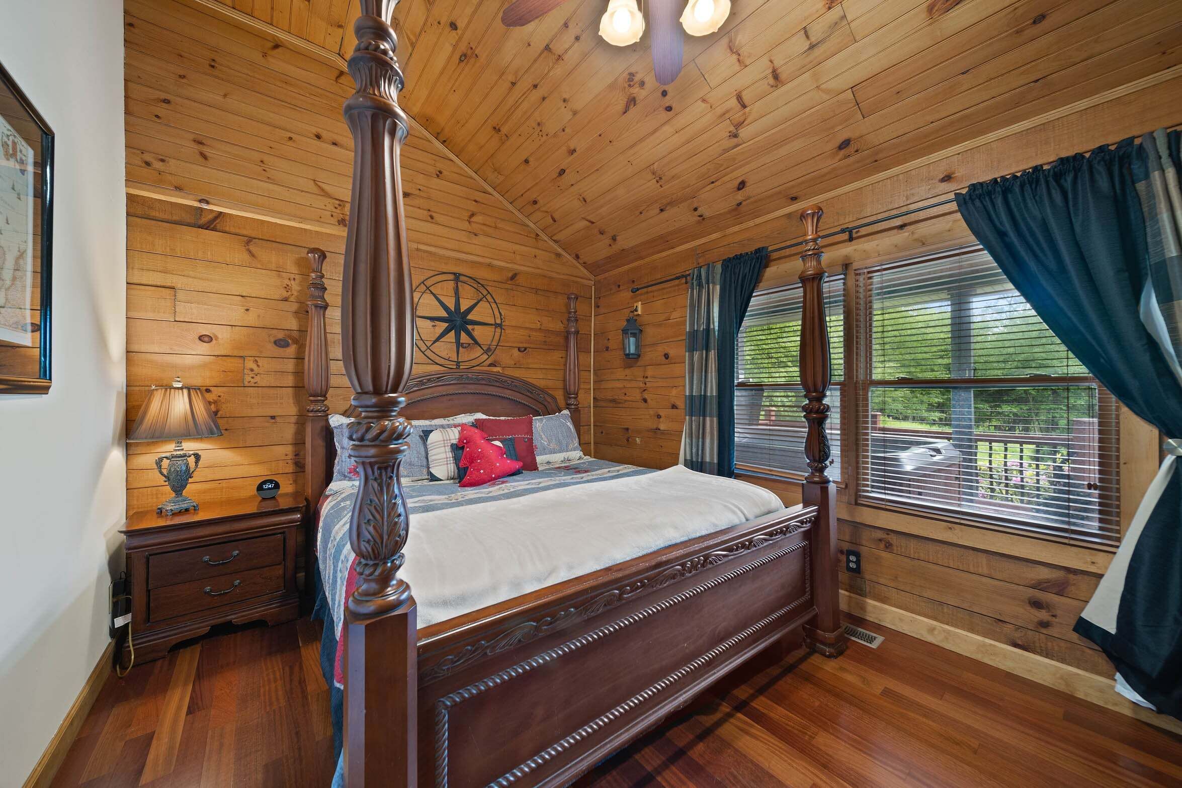 Camera da letto con pannelli in legno, un letto a baldacchino, un comodino, una lampada e una finestra con tende.