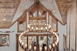 Un intérieur en bois agrémenté d’un lustre, de grandes fenêtres et d’un escalier.