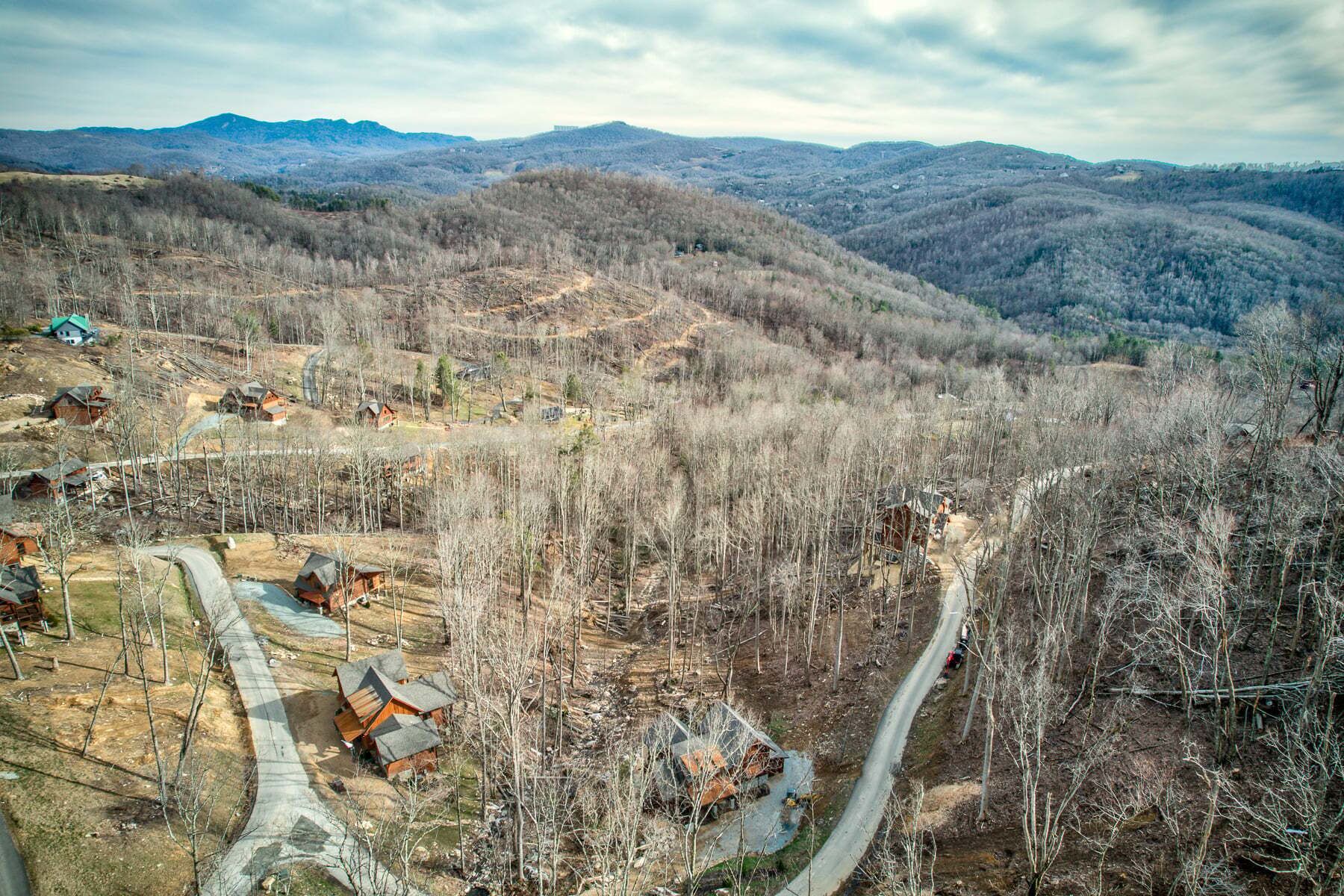 Eine gebirgige Landschaft mit verstreuten Hütten und einer kurvenreichen Straße.