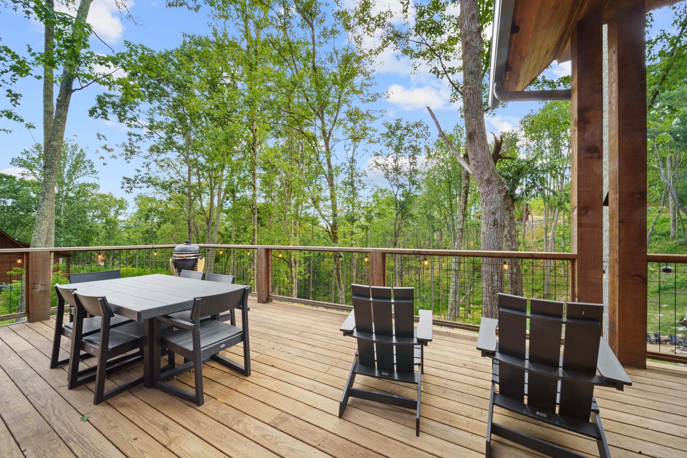 A wooden deck with a table and chairs, surrounded by trees.