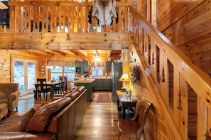 A wooden cabin interior with a dining area, kitchen, and a staircase. - Garretts Getaway at Watauga Lake (Butler)