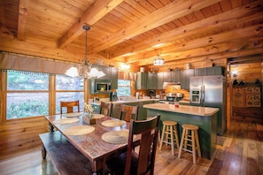 A wooden cabin with a dining area, kitchen, and large windows. - Garretts Getaway at Watauga Lake (Butler)