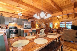 A wooden cabin interior with a kitchen, dining area, and living room. - Garretts Getaway at Watauga Lake (Butler)