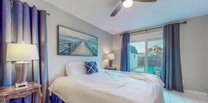 Ein Hotelzimmer mit Bett, einem Bild eines Piers, einem Deckenventilator und Blick ins Freie.