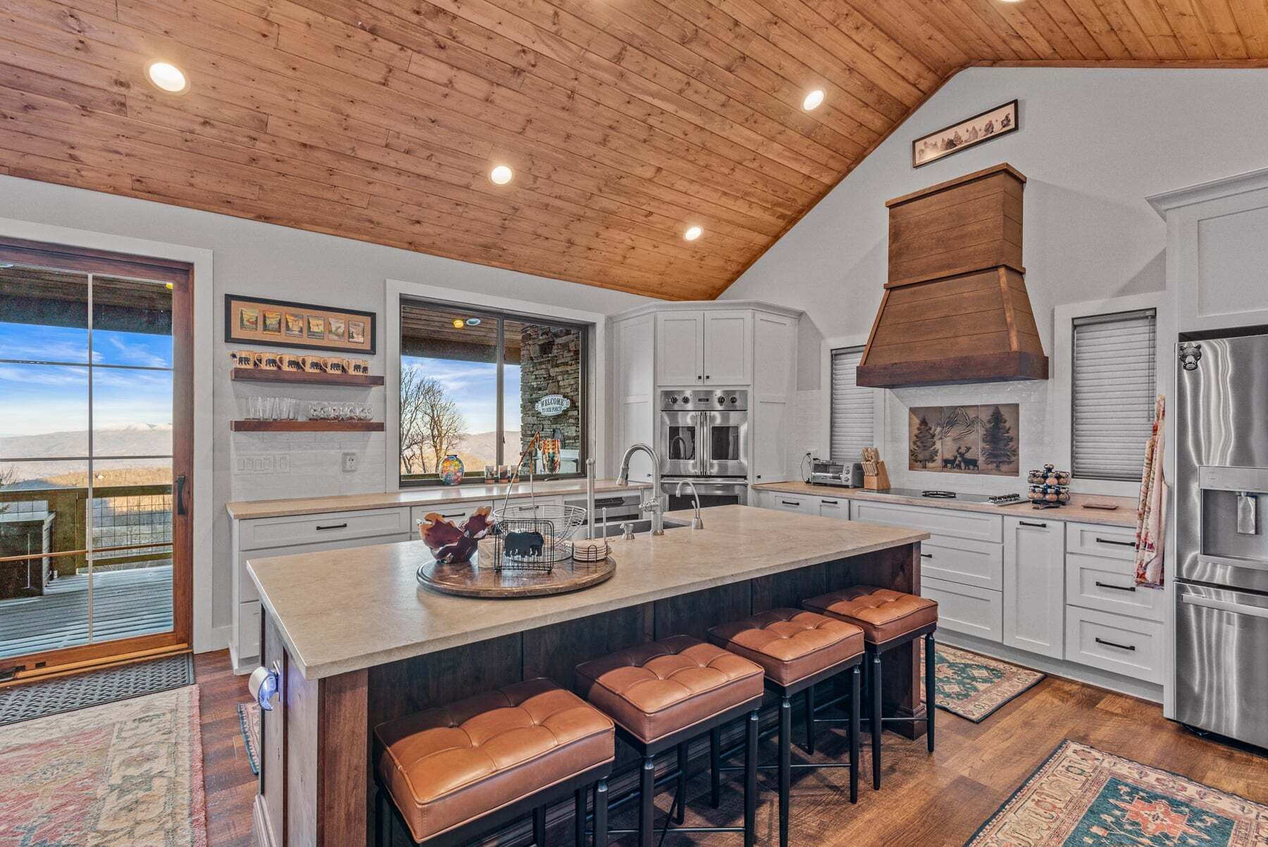 A spacious kitchen with a large island, white cabinetry, and a wooden ceiling.
