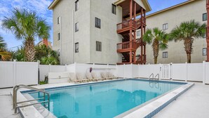 A rectangular swimming pool with a 5-foot depth marker, surrounded by white fences, and adjacent to a multi-story building with balconies. - Holiday Hideaway - Sand Castle Villas #30 (Panama City Beach)