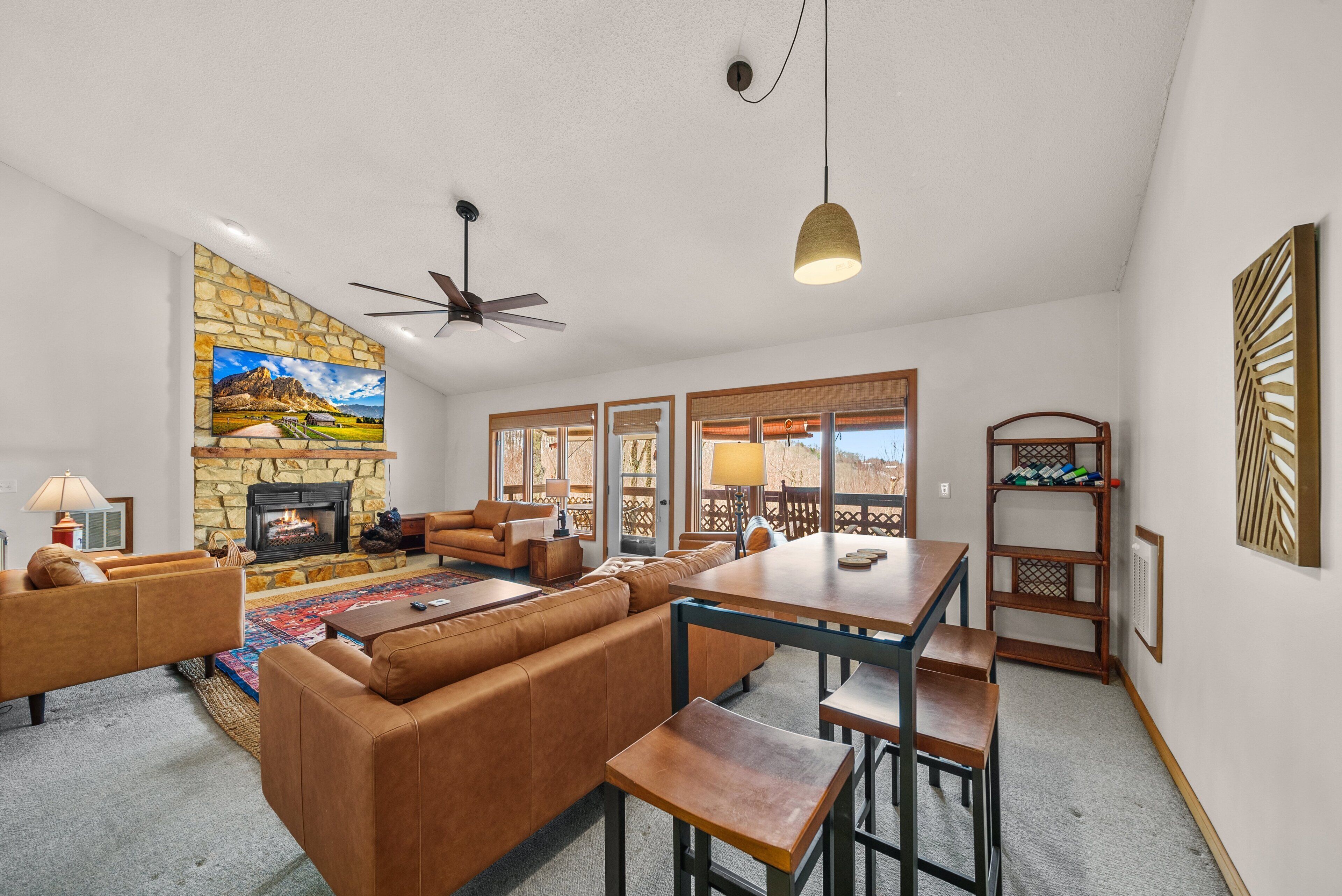 A living room with a stone fireplace, leather sofa, and a dining area with a table and chairs.