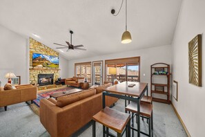 Una sala de estar con chimenea de piedra, sofá de cuero y un comedor con mesa y sillas.