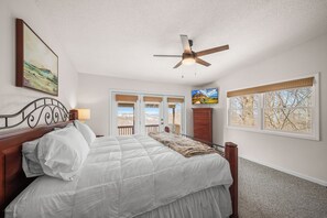 Quarto com cama, ventilador de teto, janela com vista e porta para o exterior.