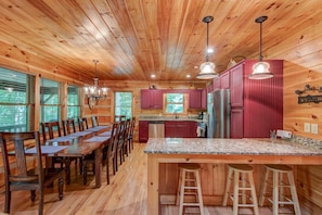 A wooden cabin interior with a dining area, kitchen, and bar stools. - Little Creek Lodge (Vilas)