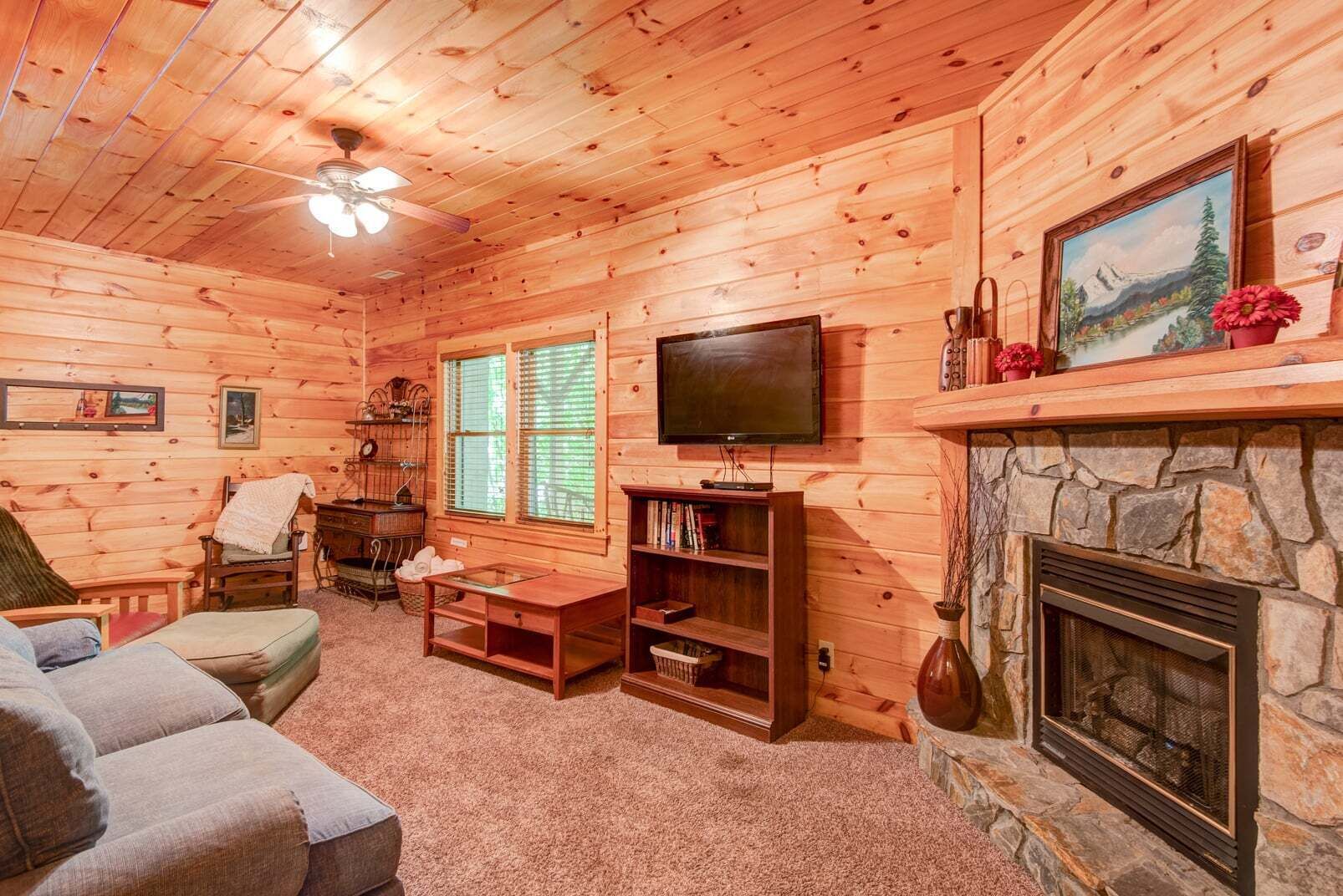 A cozy log cabin interior with a fireplace, television, and comfortable seating.