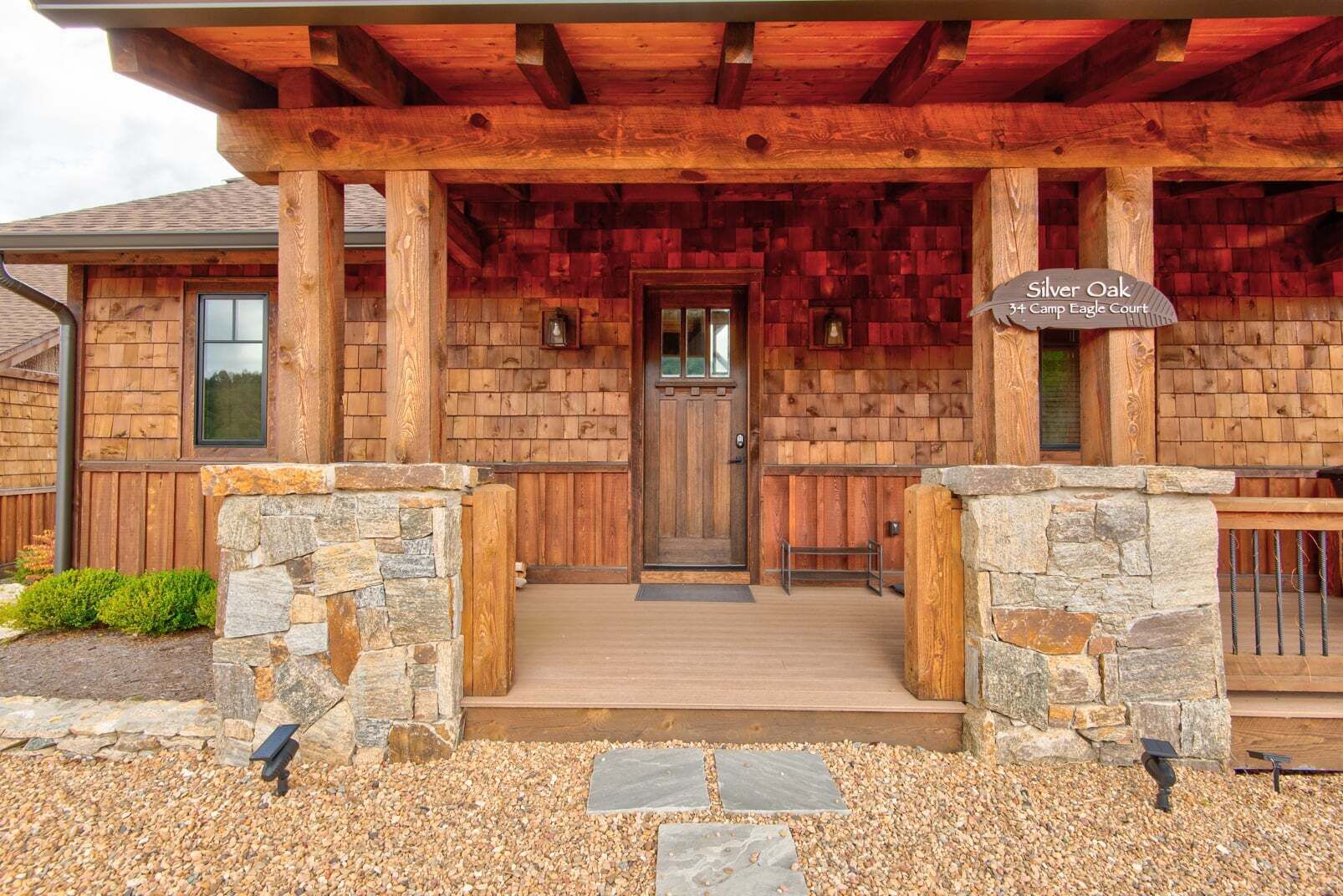 A rustic lodge entrance with a stone archway, wooden porch, and a sign reading 'Silver Oak 3+ Camp Eagle Court.'