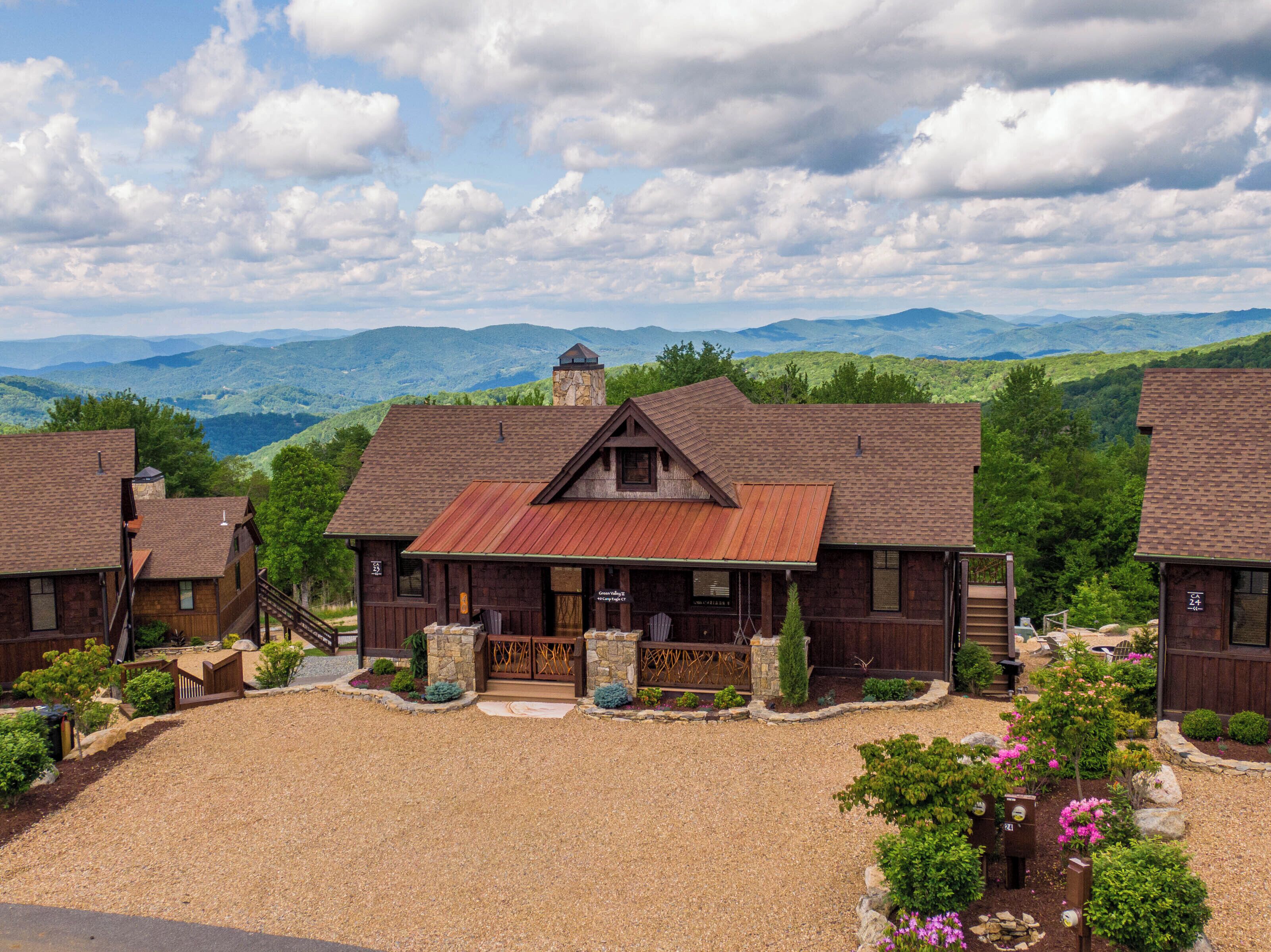 A rustic lodge with a stone chimney, wooden exterior, and a gravel driveway.