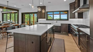 A modern kitchen with a large island, dark cabinetry, and pendant lighting. - One More Day at Eagles Nest (Elk Park)