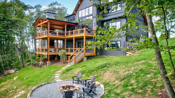 A two-story cabin with a wooden deck and a fire pit area. - One More Day at Eagles Nest (Elk Park)