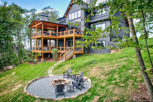 Une cabane à deux étages dotée d’une terrasse en bois et d’un espace aménagé pour faire un feu de camp.