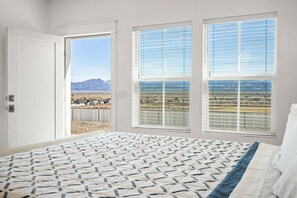 A bedroom with a large bed, two windows with blinds, and a view of a mountainous landscape. - 405 Aspen Valley - Panguitch (Panguitch)