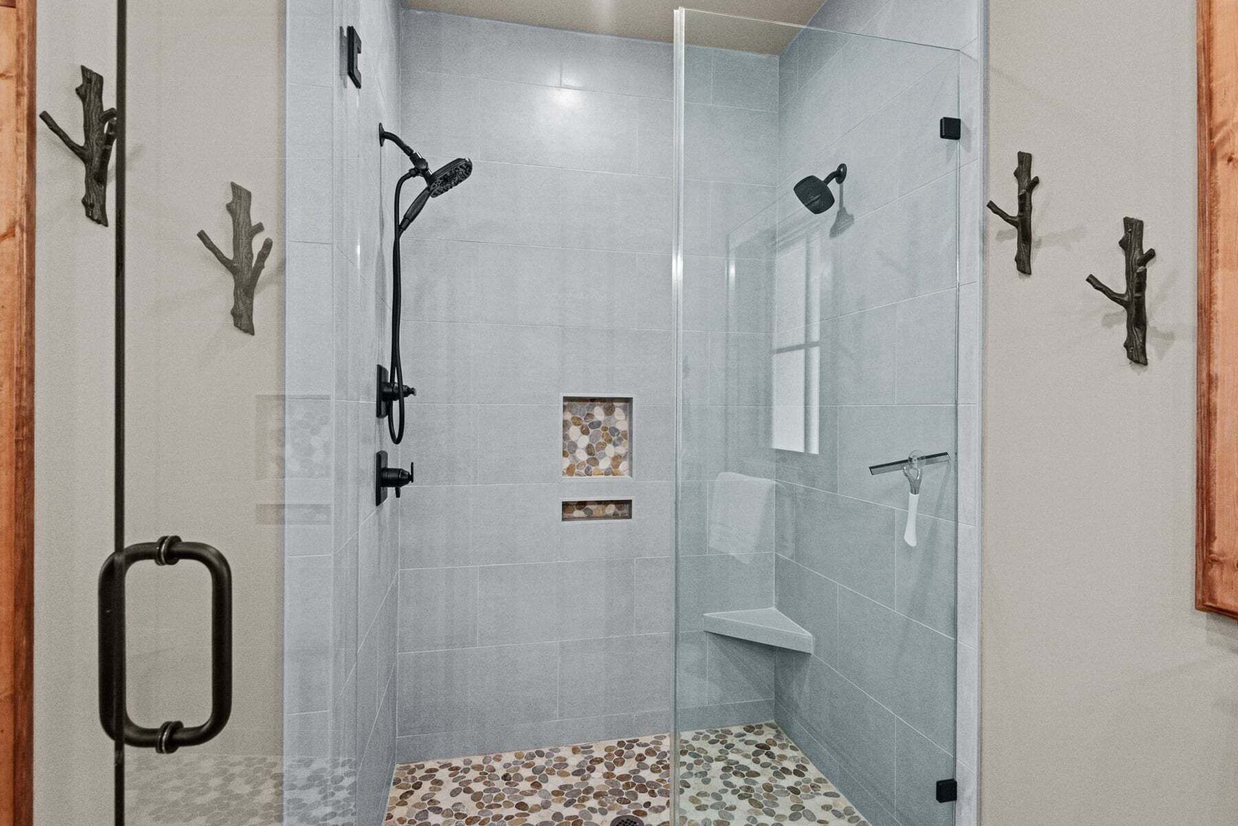 A glass-enclosed shower area with a pebbled floor, a handheld showerhead, and a wall-mounted faucet.
