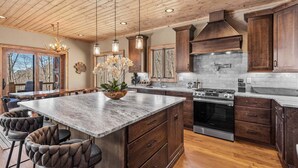 A spacious kitchen with a large island, wooden cabinets, and a built-in stove. - Rock Haven at Eagles Nest (Banner Elk)
