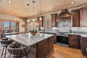 A spacious kitchen with a large island, wooden cabinets, and a built-in stove. - Rock Haven at Eagles Nest (Banner Elk)