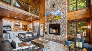 A spacious living area with a fireplace, a kitchen, and a balcony. - Cranberry View Lodge (Newland)
