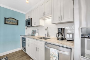 A kitchen with white cabinets, a microwave, a coffee maker, a toaster, and a dishwasher. - Bristol Breeze - Pet Friendly 2-minute Walk to Beach Ground-floo (Panama City Beach)