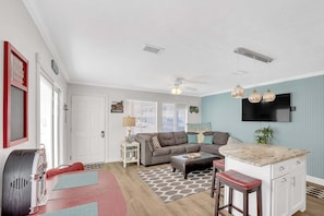 A compact living space with a kitchenette, a dining area, and a seating area with a sofa and ottoman. - Bristol Breeze - Pet Friendly 2-minute Walk to Beach Ground-floo (Panama City Beach)
