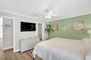 A bedroom with a bed, a ceiling fan, a TV, a dresser, and wall art. - Bristol Breeze - Pet Friendly 2-minute Walk to Beach Ground-floo (Panama City Beach)
