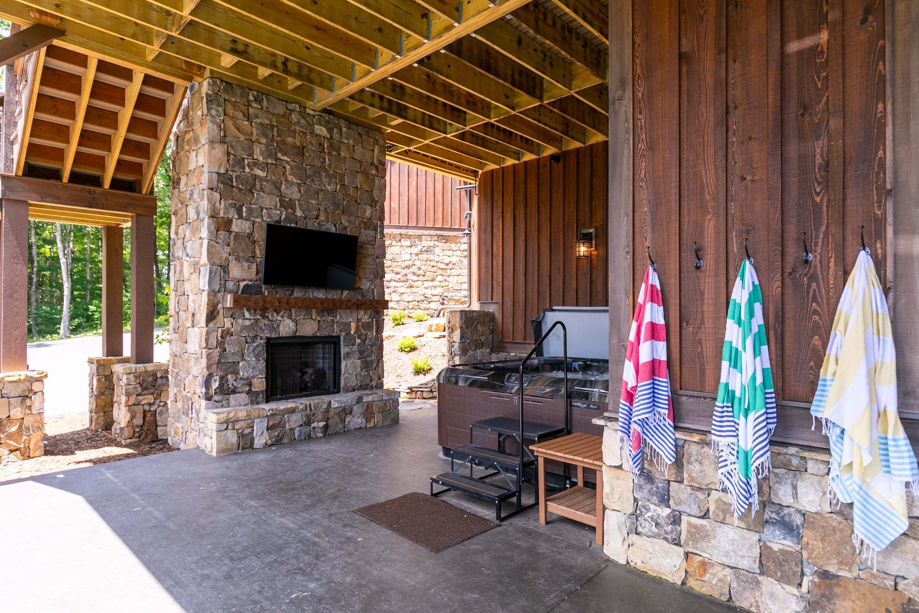 A stone fireplace, outdoor grill, and wooden pergola.