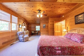 A wooden cabin bedroom with a bed, a chair, a desk, and a ceiling fan. - A Family Tradition (Boone)