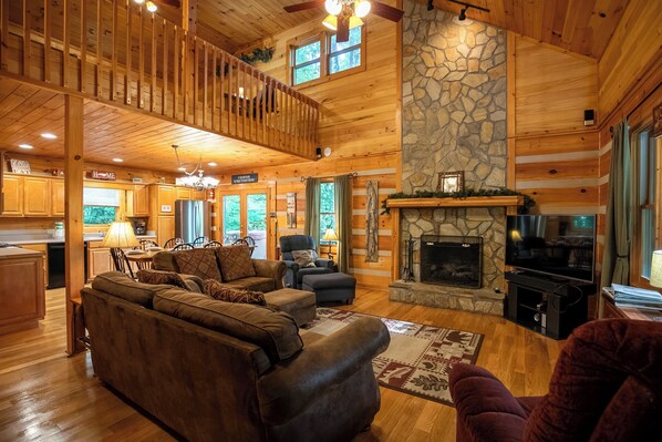 A spacious living room with a stone fireplace, wooden ceiling, and a cozy seating area. - A Family Tradition (Boone)