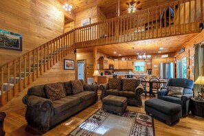 A wooden cabin interior with a staircase, living room, dining area, and kitchen. - A Family Tradition (Boone)