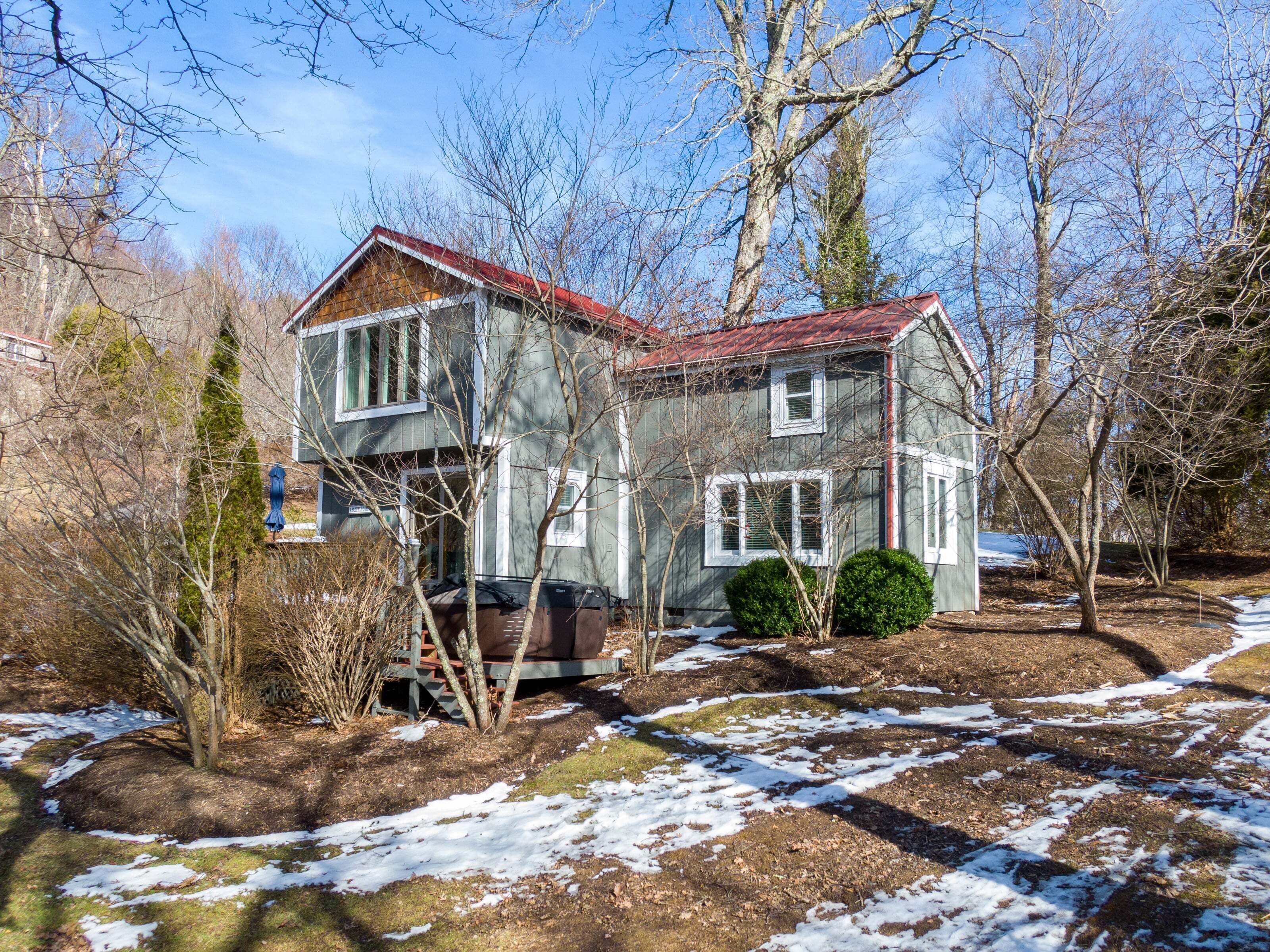 A two-story house with a red roof, surrounded by trees and a snowy ground.