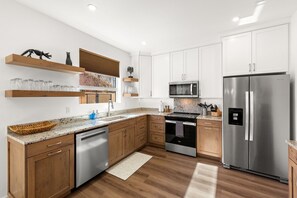 Eine moderne Küche mit Holzausstattung, Edelstahlgeräten und eingebauten Regalen.
