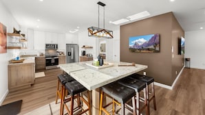 Una cocina moderna con una isla central, armarios de madera y una lámpara colgante.