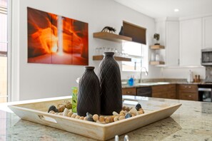 Una cocina con dos jarrones oscuros sobre una bandeja, rodeada de piedras y un adorno.