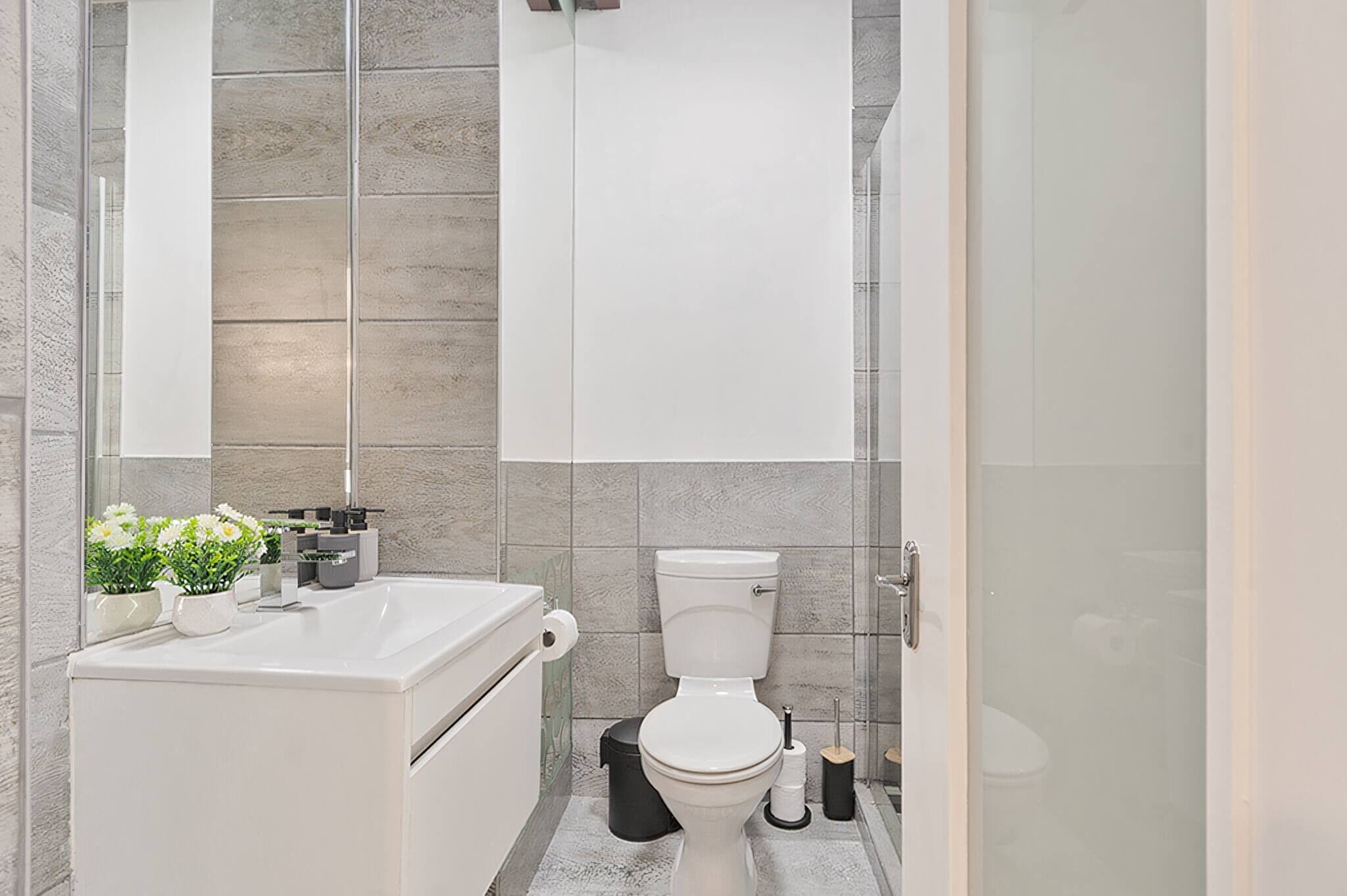 A modern bathroom with a toilet, sink, and mirror.