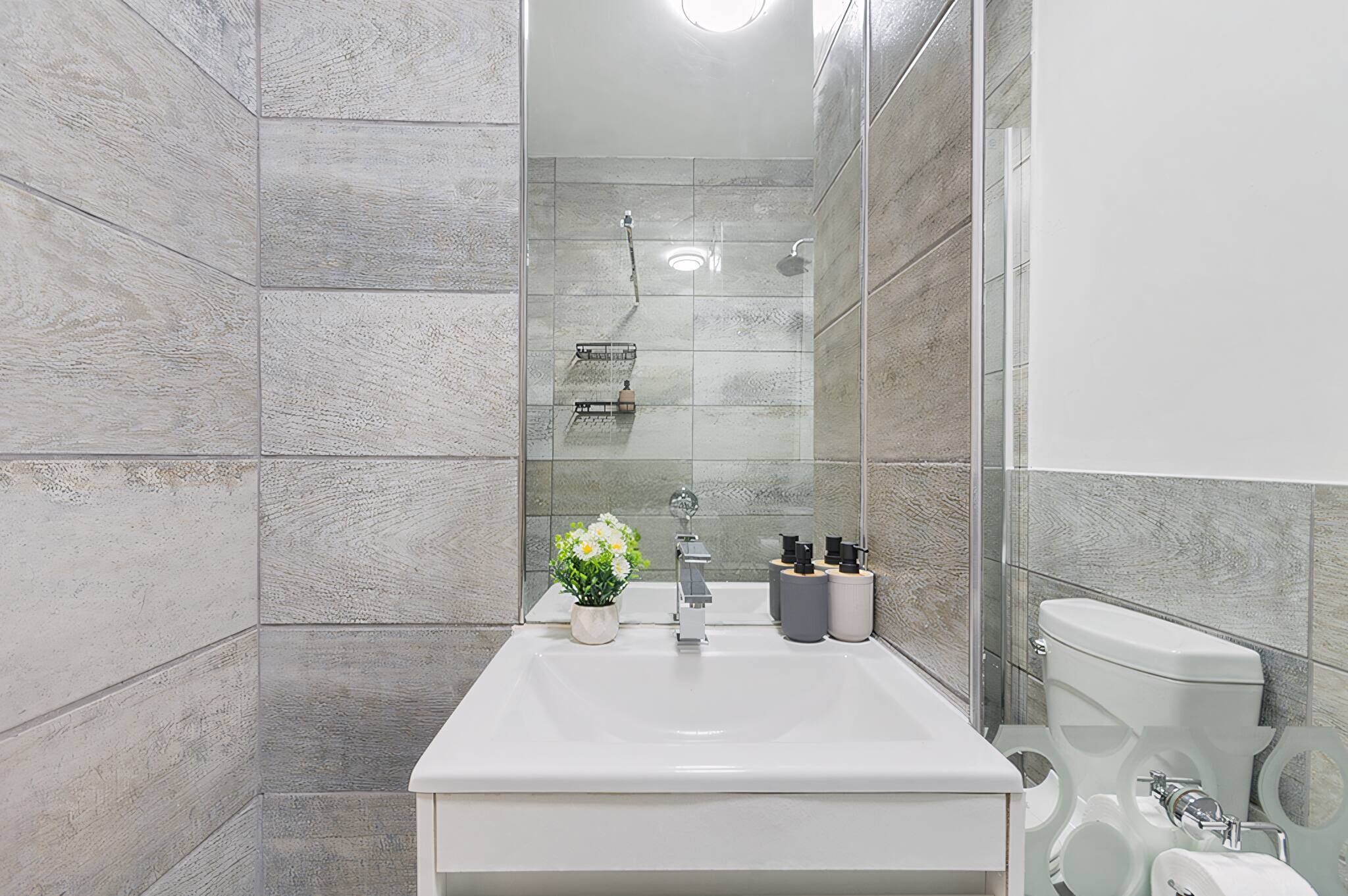 A bathroom with a shower, toilet, sink, and a small potted plant.