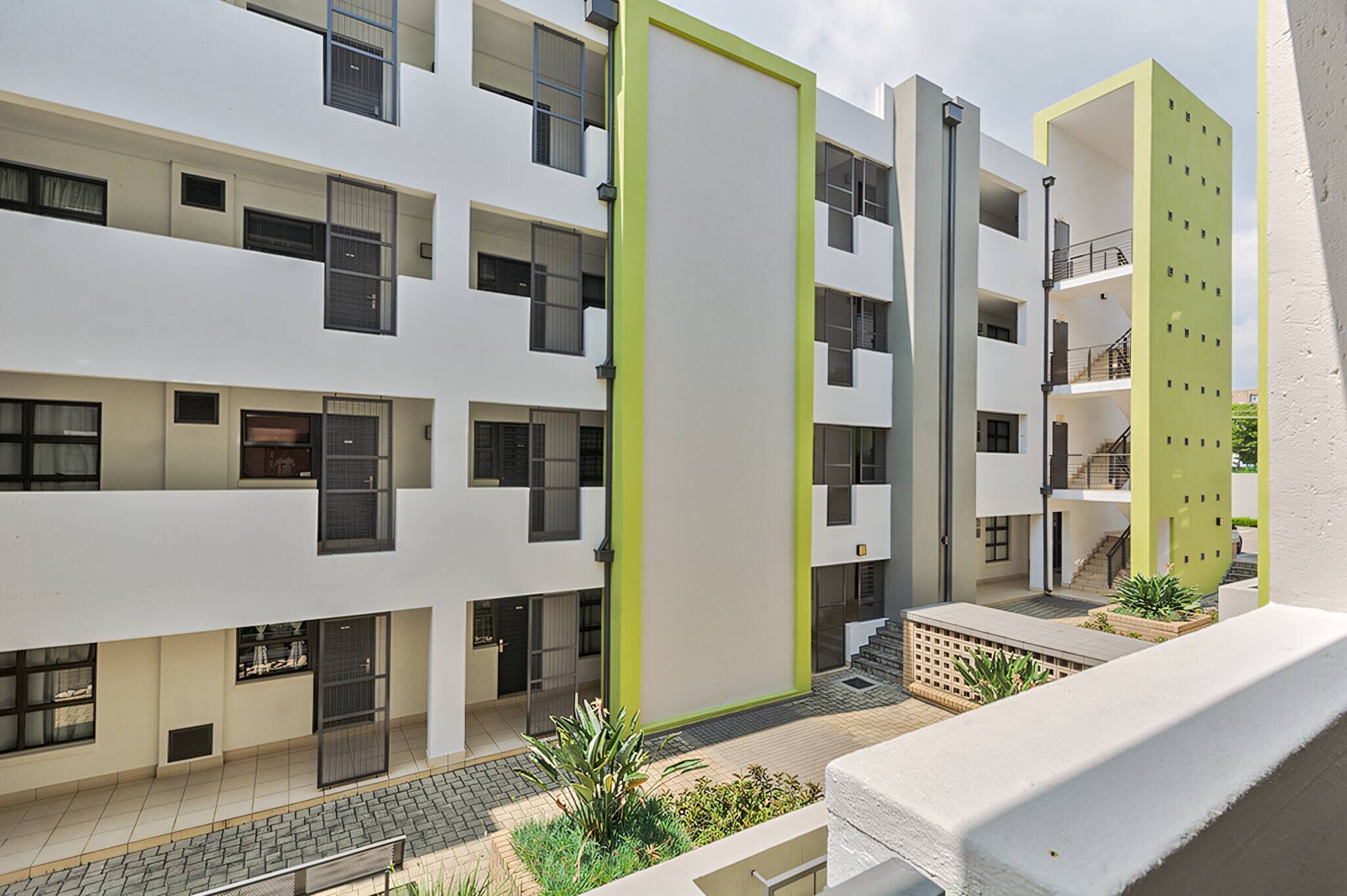 A multi-story residential building with balconies, a central courtyard, and a green accent wall.