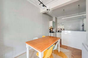 Eine moderne Küche mit weißen Schränken, einem Holztisch und einem gelben Stuhl.
