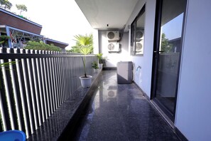A balcony with a black tiled floor, a white fence, and potted plants. - ZEALIN Stays Golf Course Road PHASE 1 (Gurugram)