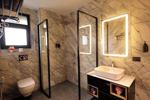 A modern bathroom with a marble wall, a white sink, a toilet, and a large mirror with illuminated edges. - ZEALIN Stays Golf Course Road PHASE 1 (Gurugram)